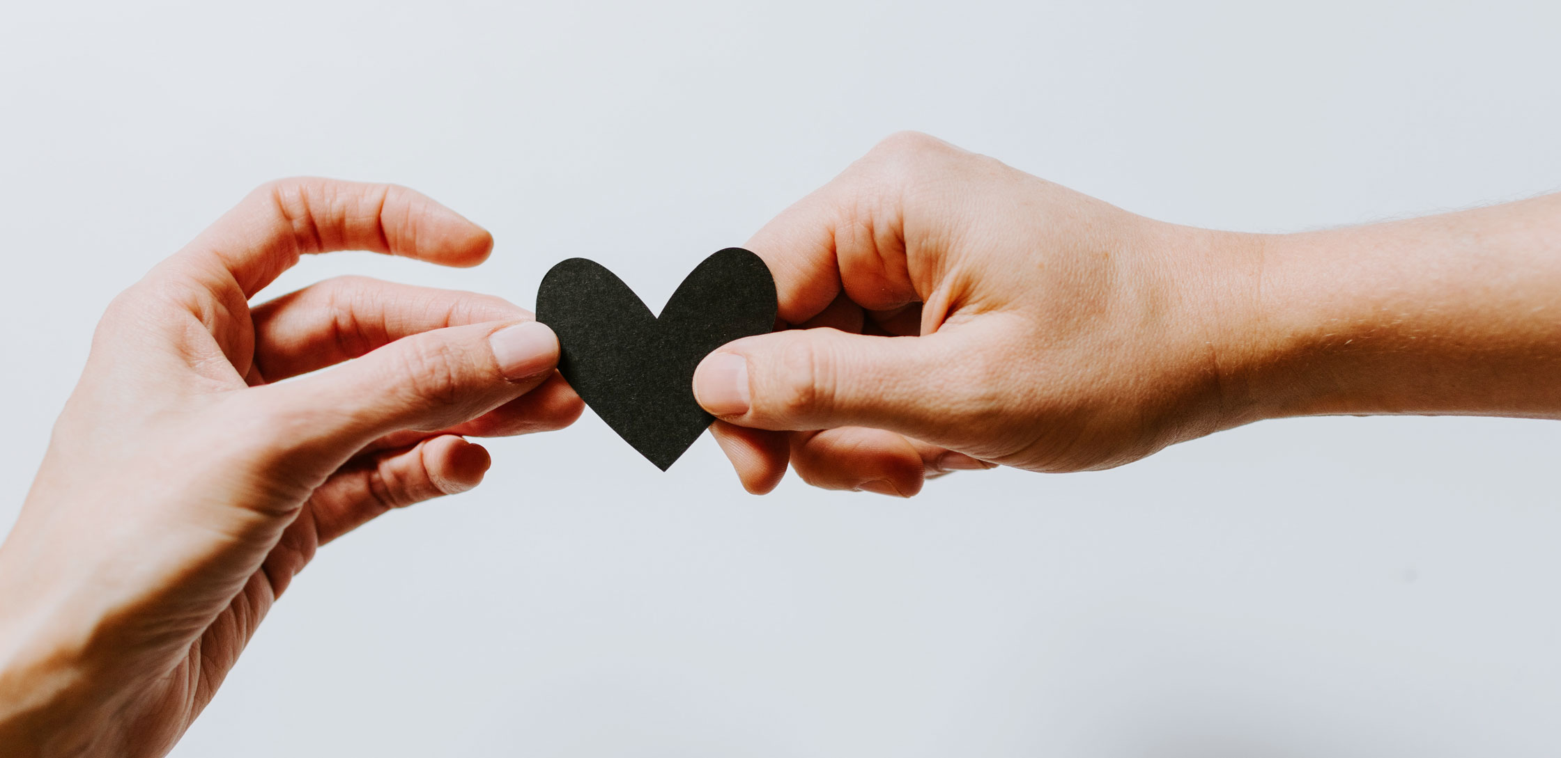 Holding black paper heart in two hands